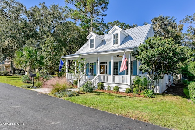 cape cod home with ceiling fan, covered porch, and a front lawn