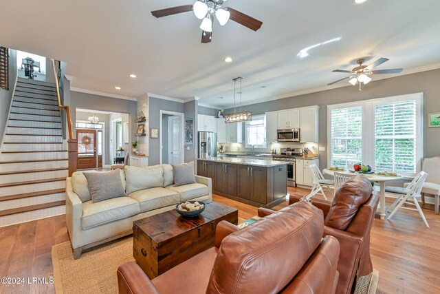 living room with crown molding, light hardwood / wood-style flooring, and ceiling fan