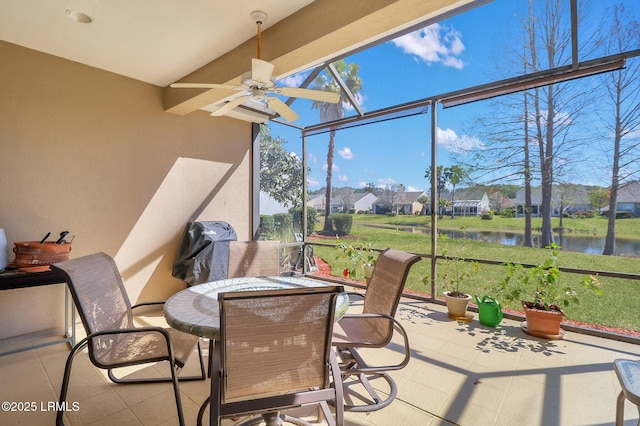 sunroom featuring beam ceiling, a ceiling fan, and a water view