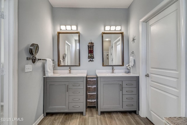 full bath with wood finished floors, two vanities, and a sink