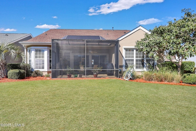 rear view of property with glass enclosure, a lawn, and stucco siding