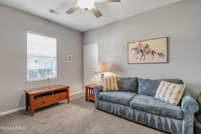 carpeted living room featuring a ceiling fan, baseboards, visible vents, and a textured ceiling