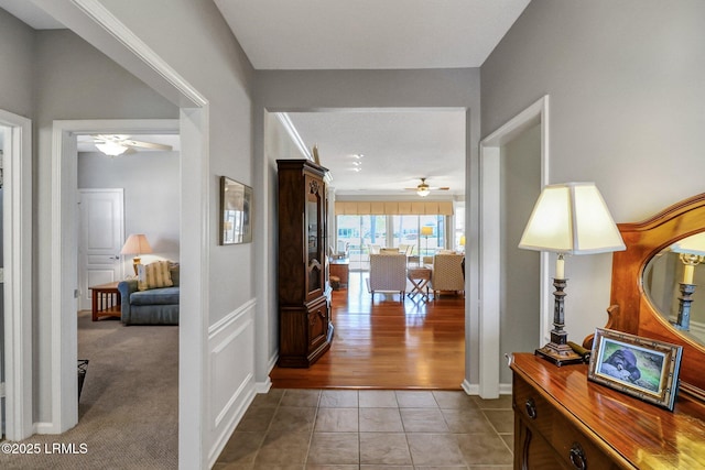 hallway with light tile patterned flooring and light carpet