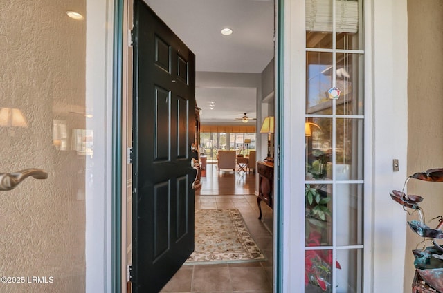 interior space with a textured wall, recessed lighting, a ceiling fan, and tile patterned flooring