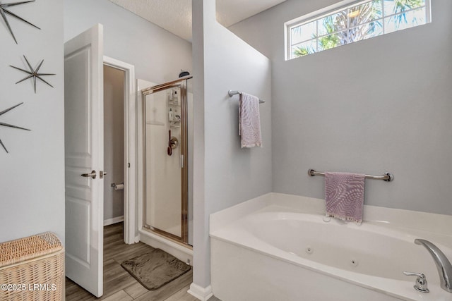 full bath with a stall shower, a jetted tub, and wood finished floors