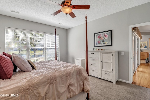 bedroom featuring visible vents, light carpet, a textured ceiling, baseboards, and ceiling fan