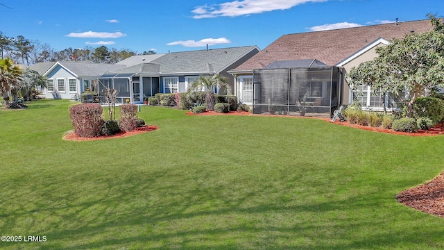 rear view of property with a lawn and a lanai