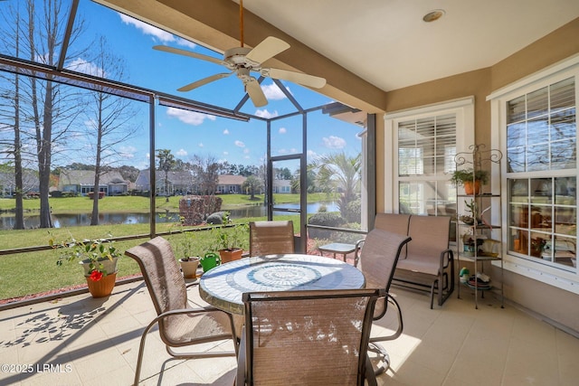 sunroom / solarium with a ceiling fan and a water view