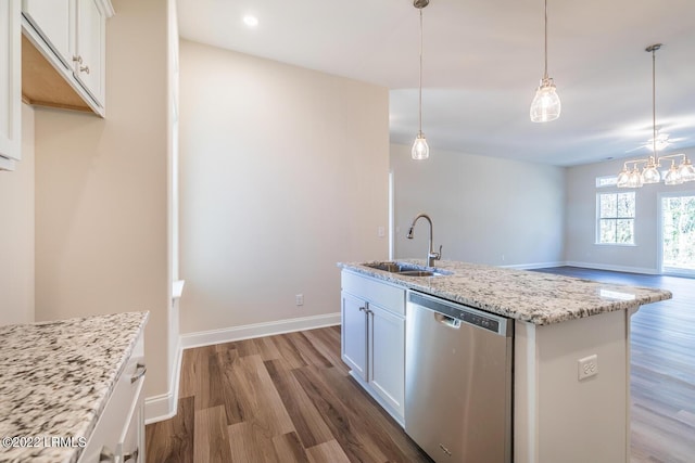 kitchen with sink, dishwasher, light stone counters, white cabinets, and a center island with sink