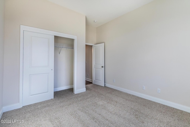 unfurnished bedroom featuring light colored carpet and a closet