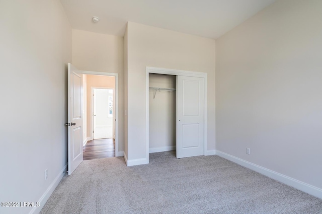 unfurnished bedroom featuring light colored carpet and a closet