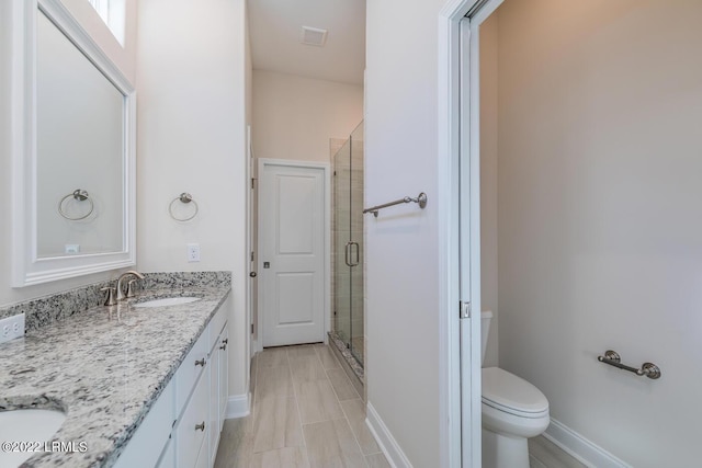 bathroom with vanity, toilet, and a shower with door