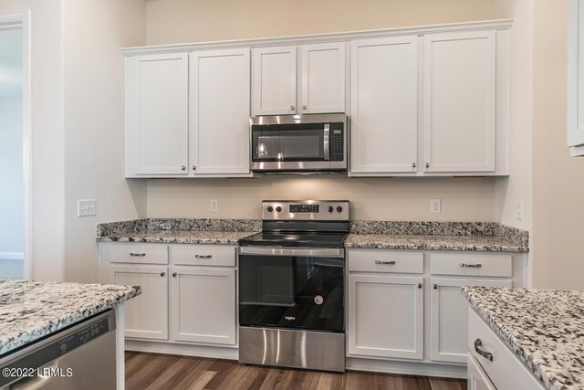 kitchen featuring white cabinetry, appliances with stainless steel finishes, dark hardwood / wood-style flooring, and light stone counters