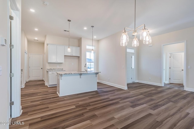 kitchen with white cabinetry, dark hardwood / wood-style floors, an island with sink, and pendant lighting