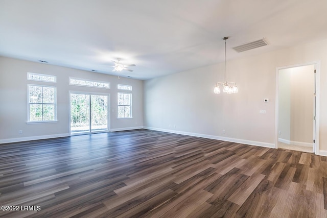 empty room with ceiling fan with notable chandelier and dark wood-type flooring