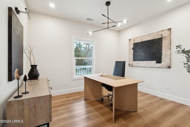 home office featuring a barn door, an inviting chandelier, and light hardwood / wood-style flooring