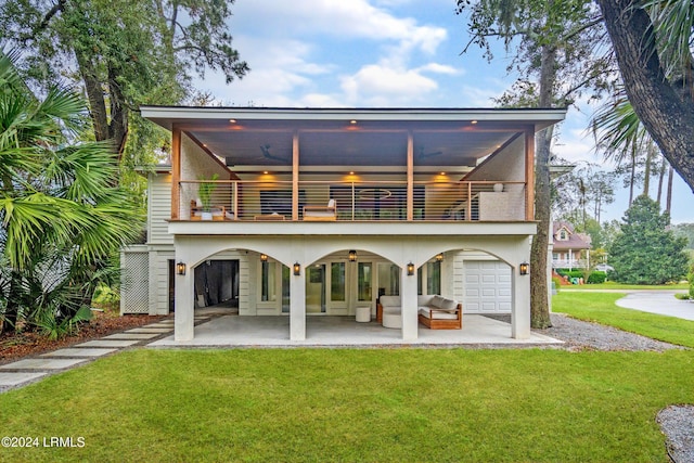 rear view of property featuring a balcony, a yard, and a patio