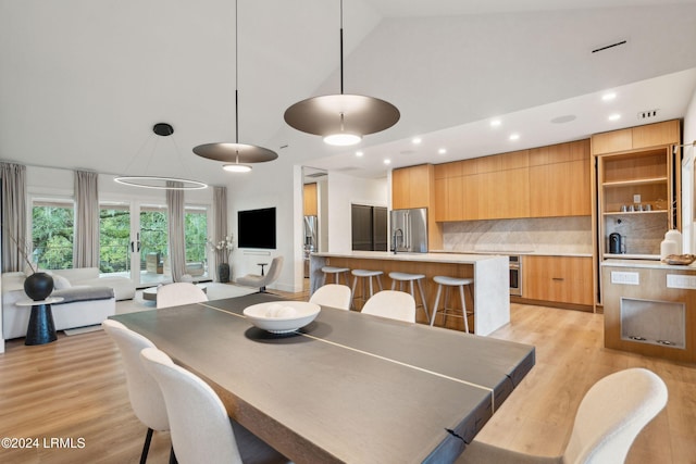 dining room featuring high vaulted ceiling, sink, and light hardwood / wood-style floors