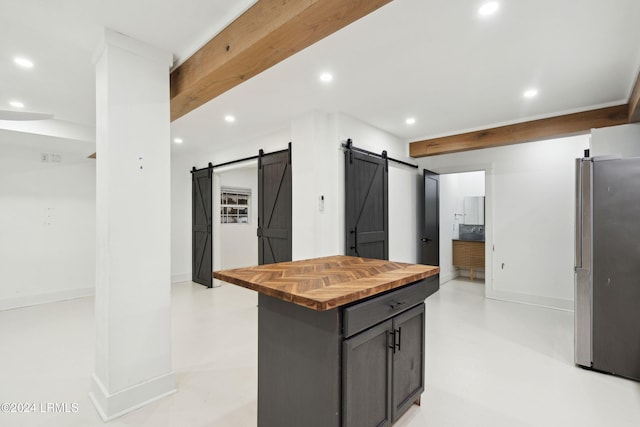 kitchen with butcher block counters, a barn door, stainless steel refrigerator, and a center island