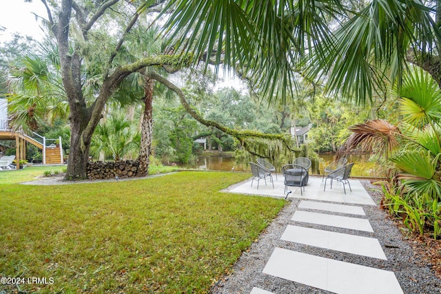 view of yard featuring an outdoor fire pit, a patio, and a water view