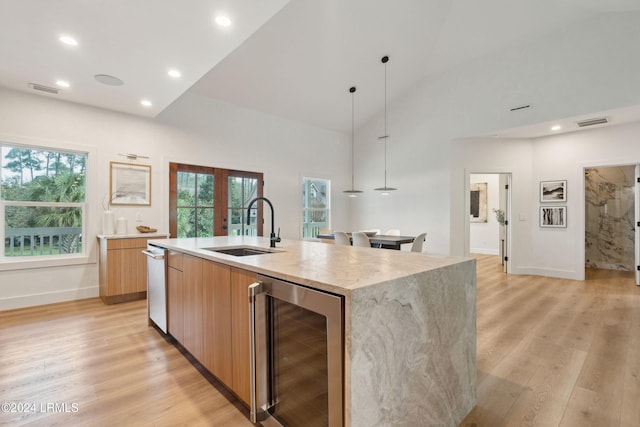 kitchen featuring wine cooler, french doors, sink, pendant lighting, and a kitchen island with sink