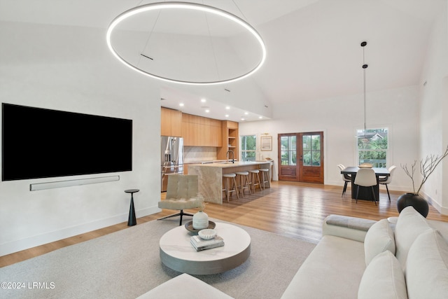 living room with french doors, sink, high vaulted ceiling, and light hardwood / wood-style flooring