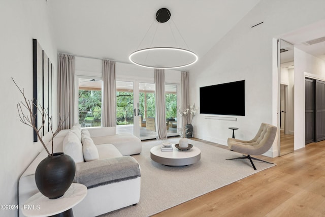 living room with vaulted ceiling, light hardwood / wood-style floors, and a healthy amount of sunlight