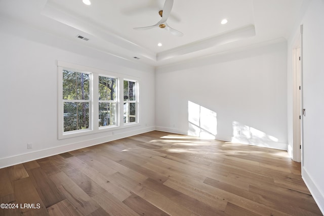 unfurnished room with wood finished floors, a raised ceiling, visible vents, and baseboards