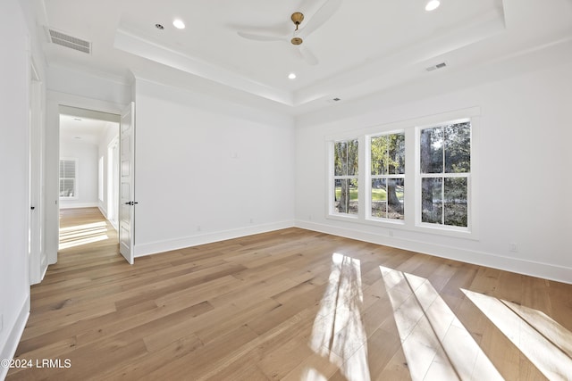 spare room with light wood-style flooring, recessed lighting, visible vents, baseboards, and a tray ceiling