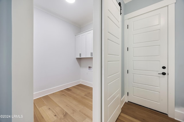 laundry room featuring a barn door, washer hookup, wood finished floors, baseboards, and cabinet space