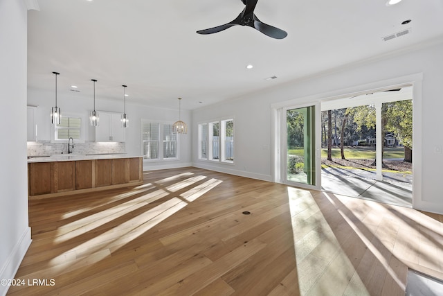 unfurnished living room with recessed lighting, ceiling fan with notable chandelier, visible vents, baseboards, and light wood-style floors