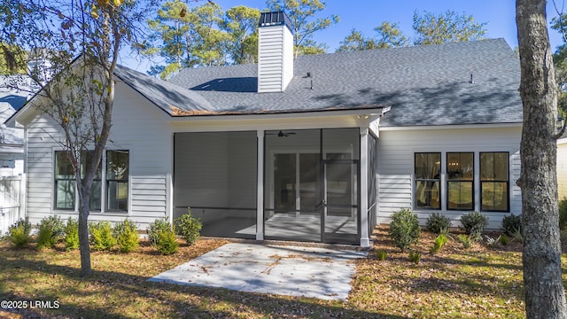 back of property with a patio, a shingled roof, a chimney, and a sunroom