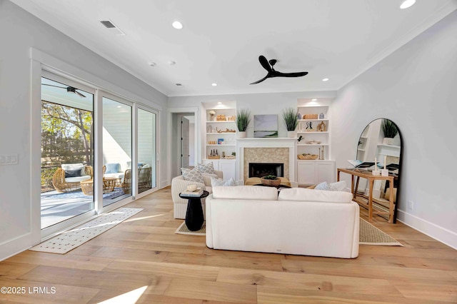 living area with baseboards, visible vents, light wood-style flooring, ceiling fan, and a fireplace