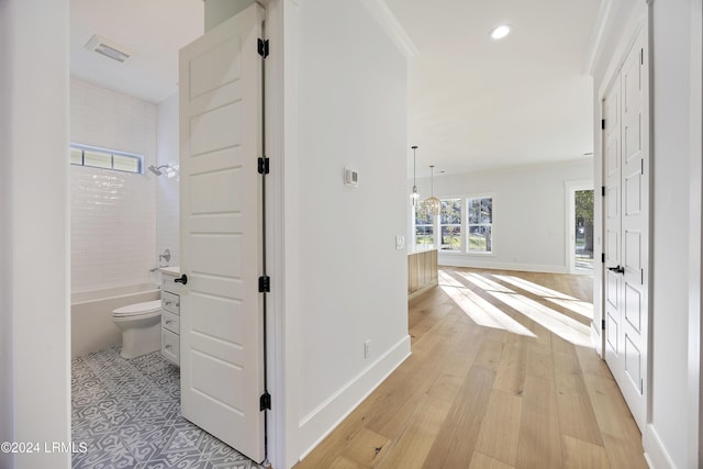 hall featuring light wood finished floors, baseboards, and recessed lighting