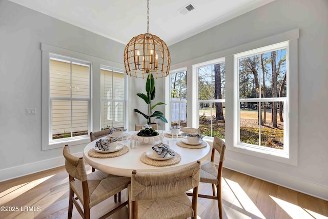 dining room with light wood-type flooring, visible vents, a notable chandelier, and baseboards