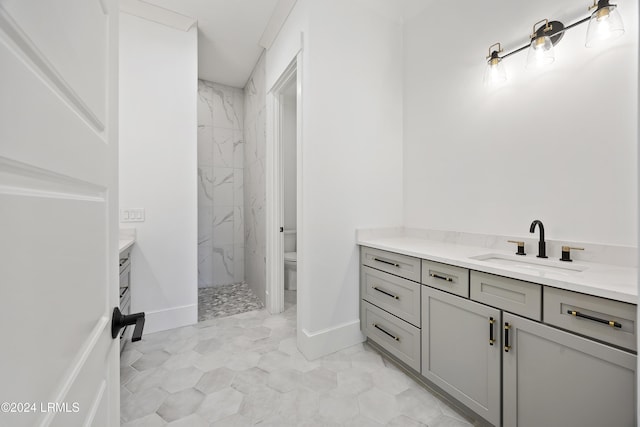 bathroom with baseboards, toilet, vanity, and a marble finish shower