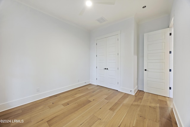 unfurnished bedroom with a closet, visible vents, baseboards, and wood finished floors