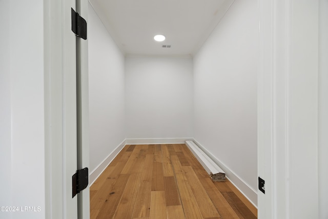 hall featuring visible vents, baseboards, and wood finished floors