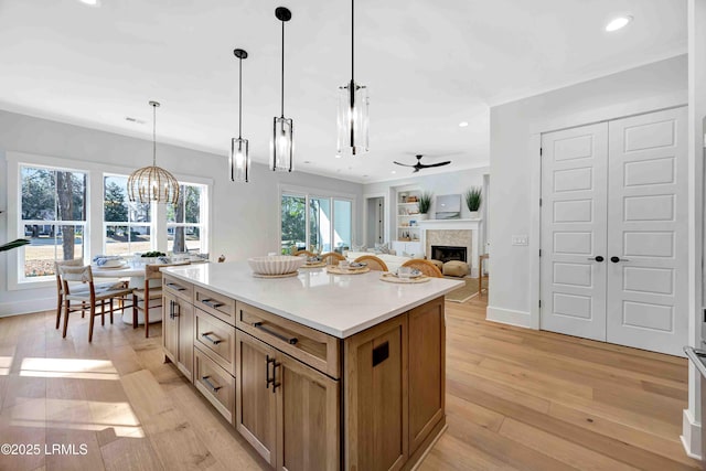 kitchen with built in features, pendant lighting, light wood-style flooring, open floor plan, and a kitchen island