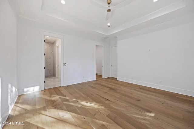 spare room featuring a tray ceiling, recessed lighting, baseboards, and wood finished floors