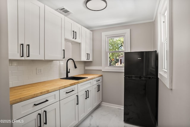 67 Sams Point Rd, Beaufort, SC 29907 - kitchen featuring crown molding, a sink, butcher block countertops, marble finish floor, and freestanding refrigerator