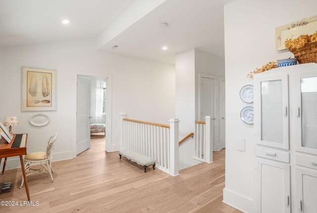 corridor with light hardwood / wood-style floors and vaulted ceiling