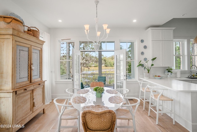 dining space featuring sink, a chandelier, and light hardwood / wood-style floors