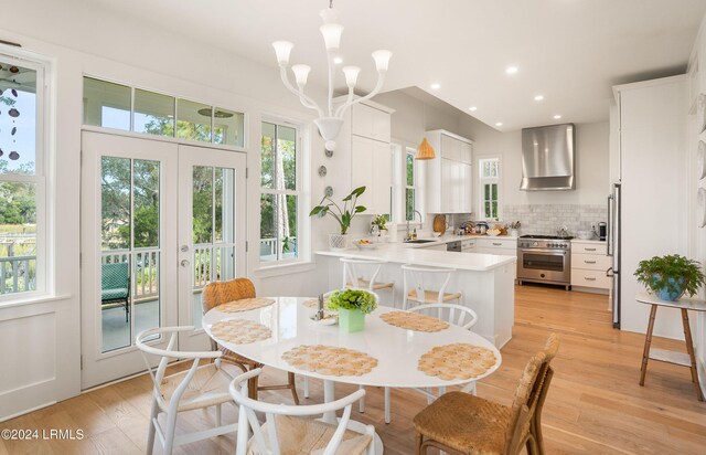 dining space with french doors, sink, light hardwood / wood-style floors, and a notable chandelier