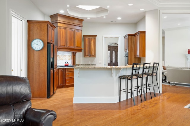 67 Winding Oak Dr, Okatie, SC 29909 - kitchen featuring open floor plan, light wood-style floors, brown cabinets, a peninsula, and high end black fridge