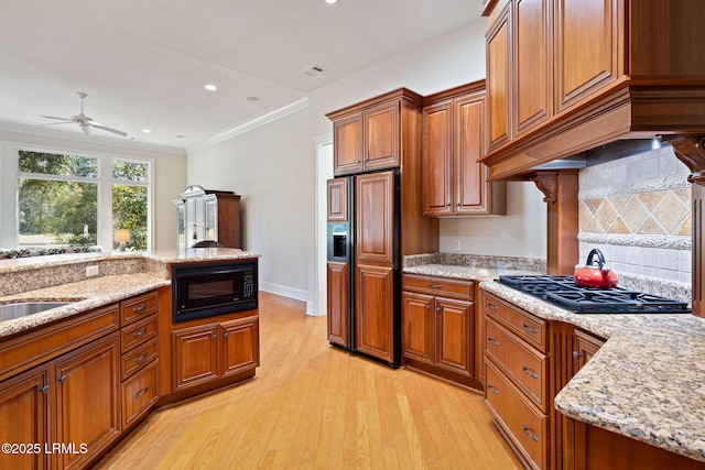 67 Winding Oak Dr, Okatie, SC 29909 - kitchen with black appliances, brown cabinets, light wood-style flooring, a ceiling fan, and ornamental molding