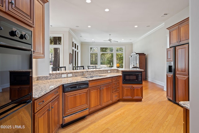 67 Winding Oak Dr, Okatie, SC 29909 - kitchen with black appliances, light wood finished floors, brown cabinetry, recessed lighting, and crown molding