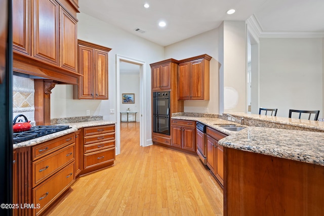 67 Winding Oak Dr, Okatie, SC 29909 - kitchen with a sink, black appliances, light wood-style flooring, brown cabinetry, and light stone counters