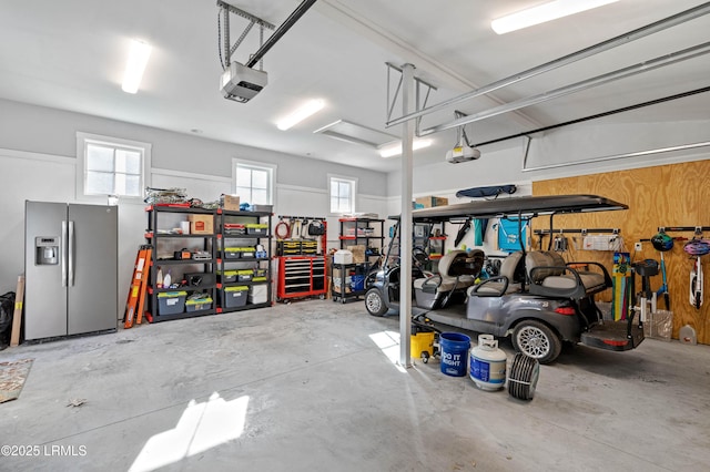 garage featuring a garage door opener and stainless steel fridge with ice dispenser