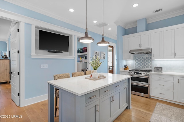 kitchen with a breakfast bar, double oven range, a center island, ornamental molding, and decorative light fixtures